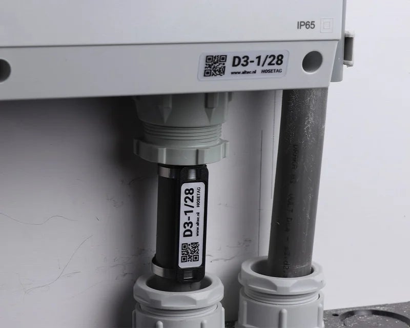 HoseTag bevestigd aan een leiding of kabel bij een kabelwartel van een industriële kast