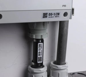 HoseTag bevestigd aan een leiding of kabel bij een kabelwartel van een industriële kast