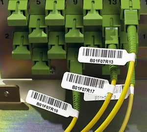 Witte vlaglabels met barcode en identificatiecode op gele glasvezelkabels