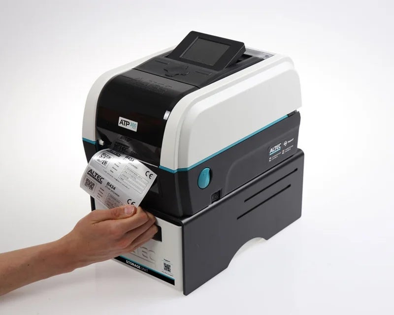 Gebruiker verwijdert een geprint label uit een ATP-300 Pro labelprinter die geplaatst is op een ATP Storage Unit