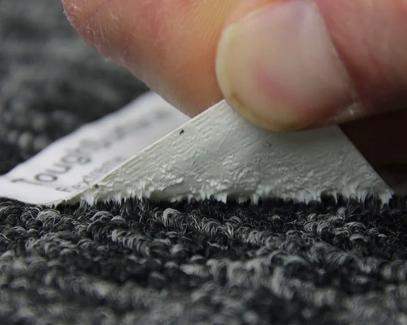 Hand verwijdert ToughSurface Flextreme label van tapijtoppervlak