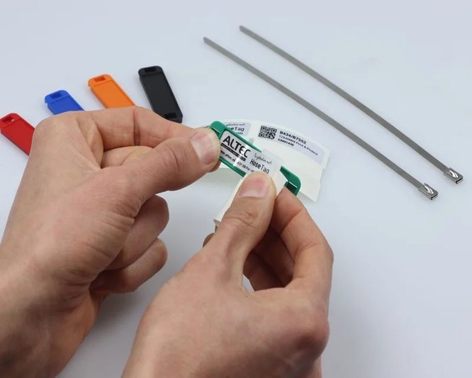 Handen plaatsen een Print & Protect label in een groene HoseTag