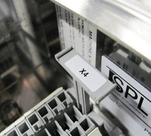 Wit componentlabel met codering geplaatst in een elektrische besturingskast