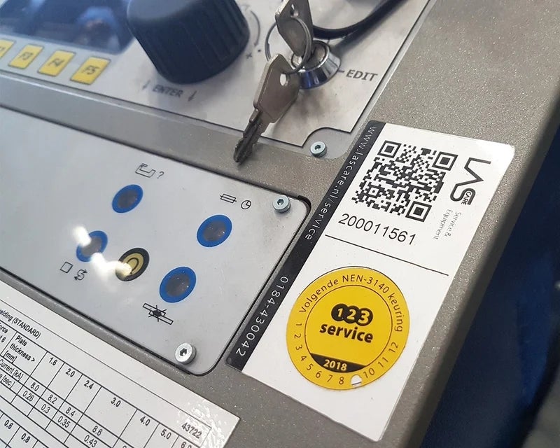 Keuringslabel en label met QR-code aangebracht op industriële machine