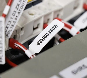 Wit vlaglabel met identificatiecode op rode ader in schakelkast