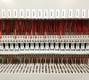 Witte ResoPrint labels met componentcodes op relais bij klemmenstroken in schakelkast, als duurzaam alternatief voor resopal labels