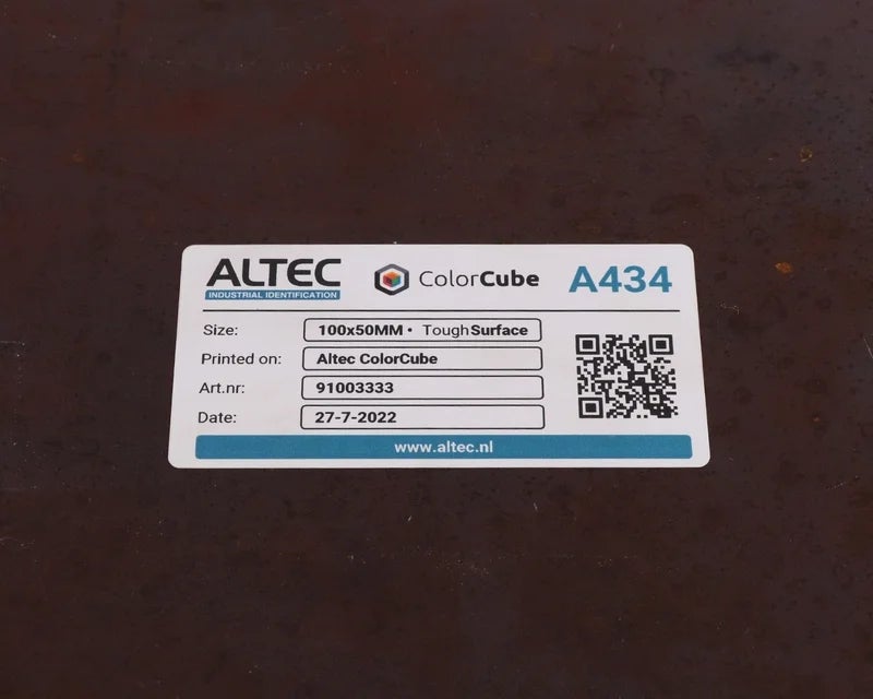 Full-color label met tekst en QR-code aangebracht op ruwe metalen ondergrond