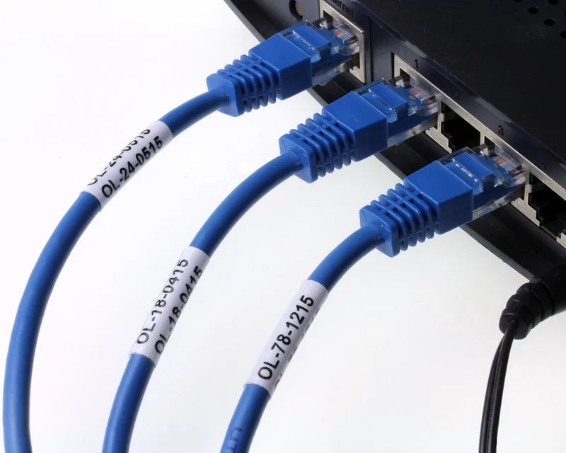Witte wikkellabels met identificatiecodes op blauwe netwerkkabels aangesloten op netwerkswitch voor kabelcodering