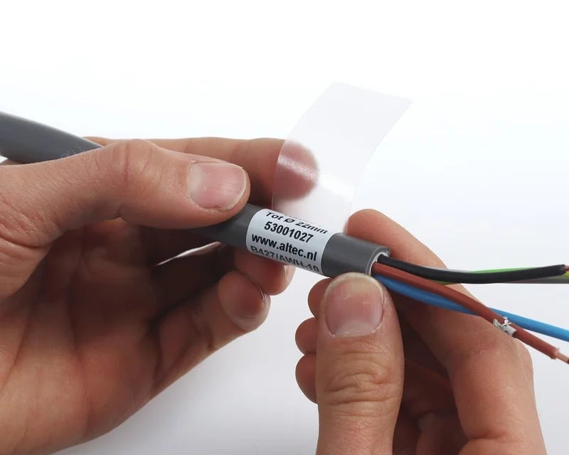 Handen die een transparant wikkellabel aanbrengen op grijze kabel met kleuraders