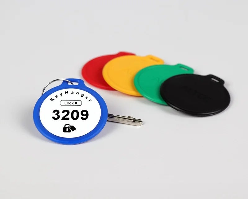 Blauwe KeyHanger met unieke nummering bevestigd aan een sleutel met meerdere gekleurde sleutelhangers op de achtergrond