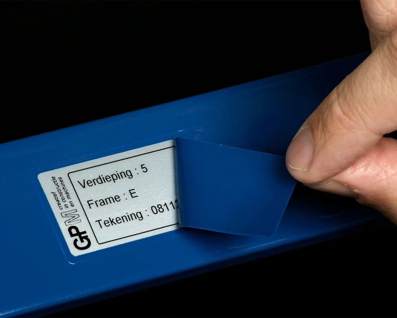 Verwijderen van het PaintLabel maskeerlaminaat na het oppervlaktebehandelingsproces, waarbij het label zichtbaar wordt op een blauw onderdeel