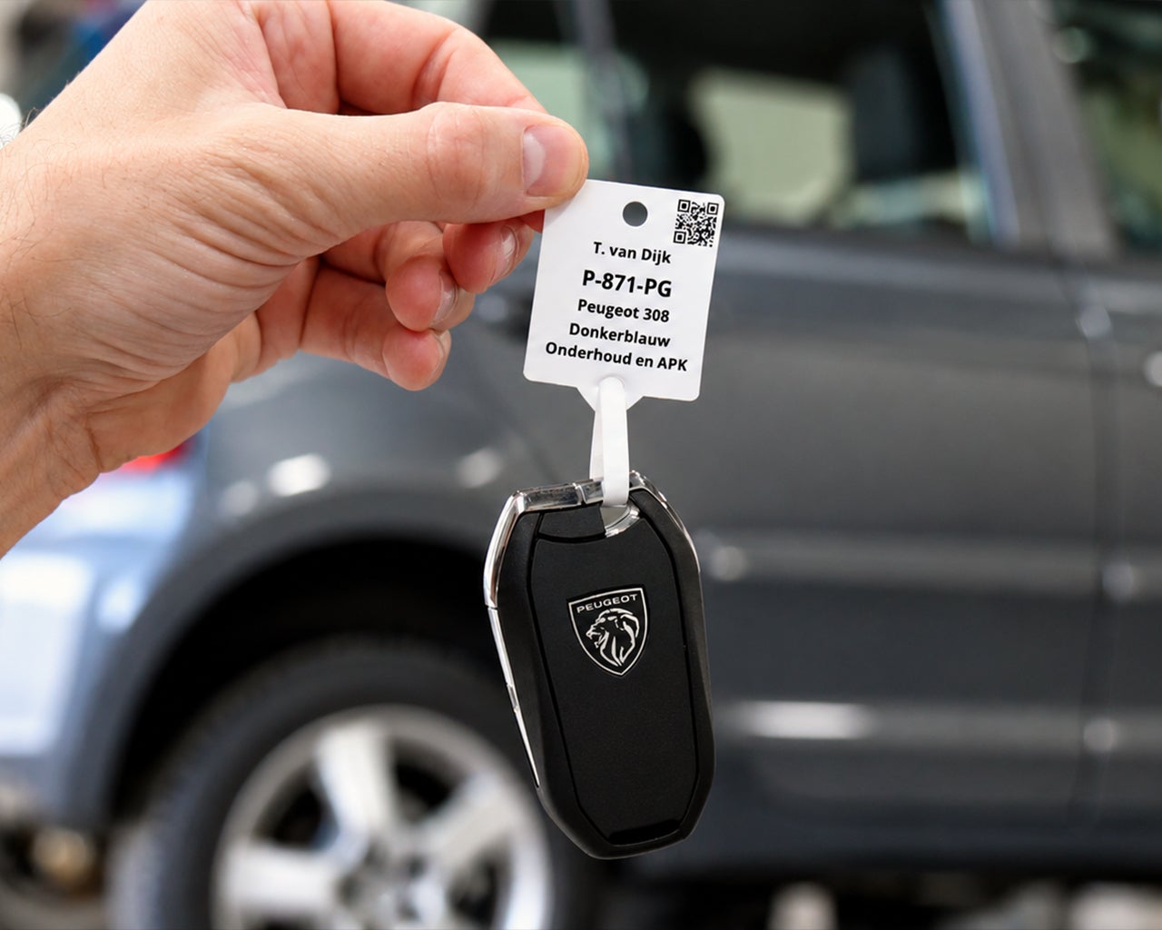 Bedrukt sleutellabel met voertuig- en klantinformatie zoals een QR-code bevestigd aan een autosleutel