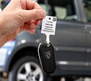 Bedrukt sleutellabel met voertuig- en klantinformatie zoals een QR-code bevestigd aan een autosleutel