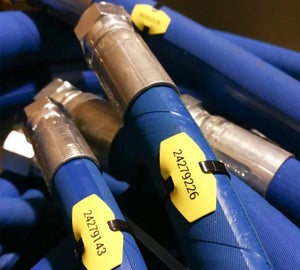 Gele kabelmerkers met serienummers op blauwe hydraulische slangen met stalen koppelingen