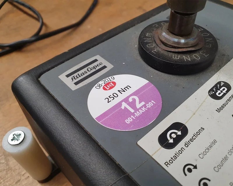 Rond keuringslabel met inspectiedatum en specificaties op industrieel meetapparaat