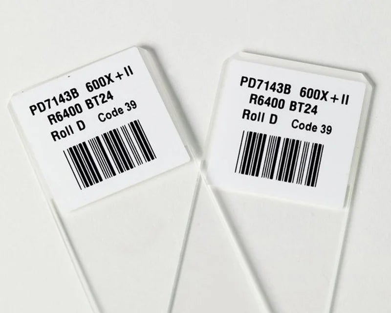 Witte objectglaslabels met barcode en tekst aangebracht op transparante objectglaasjes voor laboratoriumidentificatie