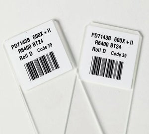 Witte objectglaslabels met barcode en tekst aangebracht op transparante objectglaasjes voor laboratoriumidentificatie