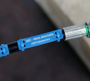 Blauwe metal detectable kabelmerker bevestigd rond een industriële kabel met bedrukte identificatie