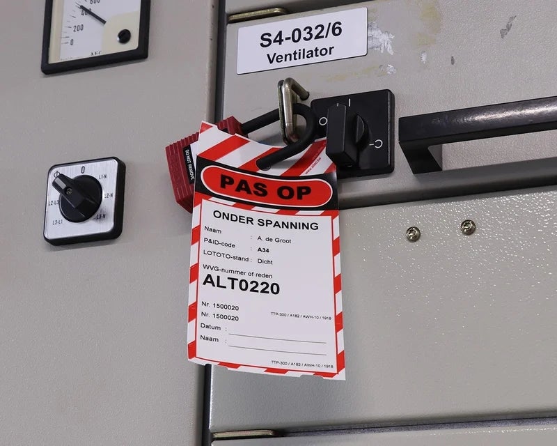 Gevarentag met waarschuwing onder spanning bevestigd aan elektrische schakelkast