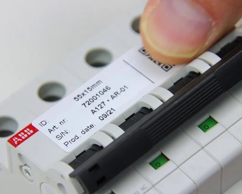 Wit componentlabel met serienummer en productinformatie aangebracht op elektrische installatieautomaat