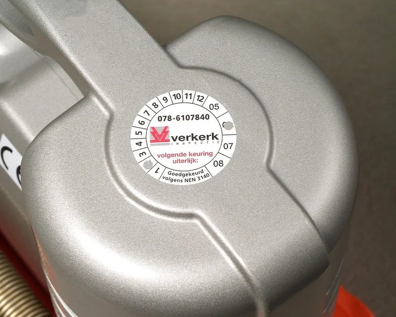 Rond keuringslabel met inspectiegegevens aangebracht op metalen oppervlak