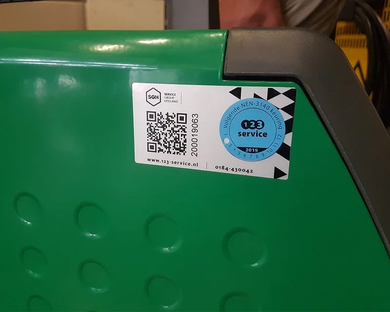 Keuringslabel met QR-code en inspectiesticker aangebracht op groene machinebehuizing