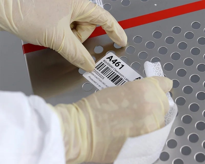 Cleanroom label met barcode wordt gereinigd op roestvrijstalen oppervlak in cleanroom omgeving.