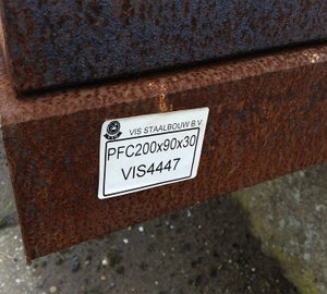 Wit ToughSurface Extreme label aangebracht op geroest staalprofiel in industriële omgeving