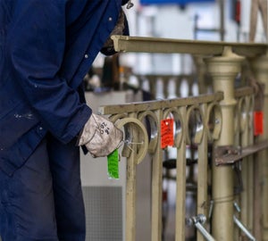 Medewerker bevestigt WetPaintCard aan hek voor identificatie tijdens oppervlaktebehandeling