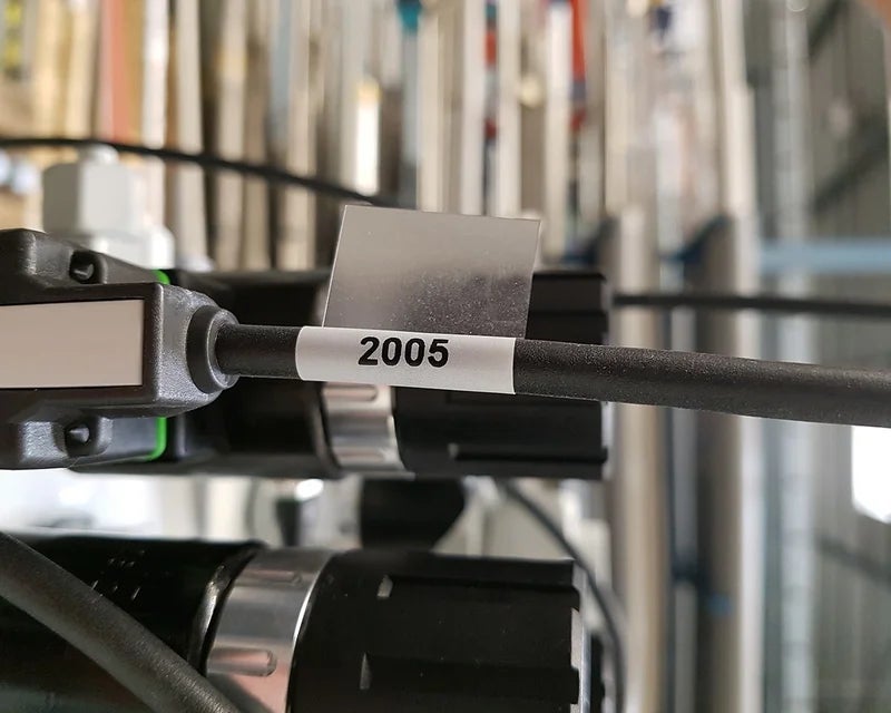 Witte wikkellabel met nummercode op zwarte kabel