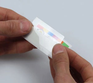 Handen die het transparant beschermlaminaat aanbrengen over een Full-color Print & Laminate label