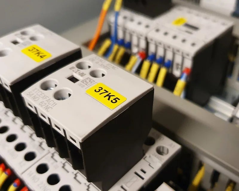 Gele componentlabels aangebracht op contactoren in industriële schakelkast