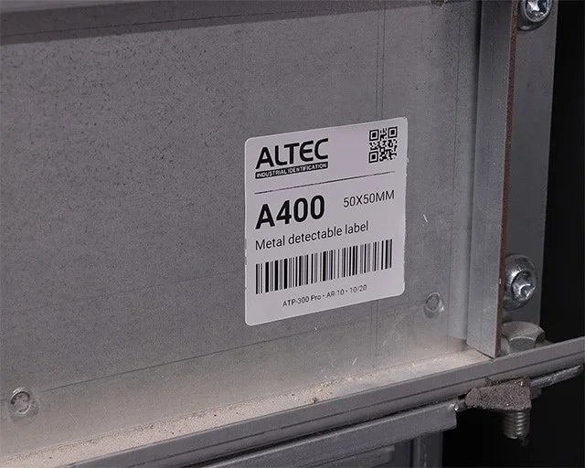 Metal detectable label met barcode en QR-code aangebracht op een metalen industriële behuizing