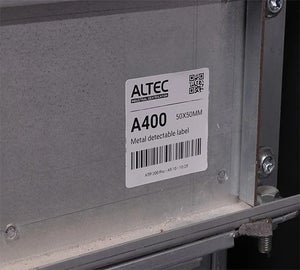 Metal detectable label met barcode en QR-code aangebracht op een metalen industriële behuizing