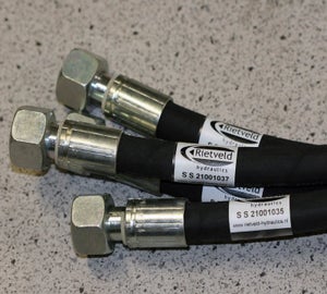 Witte wikkellabels met bedrijfslogo en serienummer op zwarte hydraulische slangen