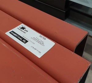 Wit ToughSurface Extreme label aangebracht op rood gelakte staalbundel