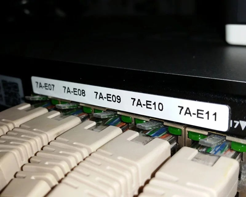 Witte ResoPrint labels met poortcodering op patchpaneel met aangesloten netwerkkabels