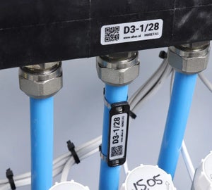 Zwarte HoseTag met QR-code bevestigd aan een slang naast een metalen koppeling