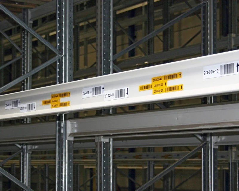 Gele en witte magazijnlabels op een magazijnrek met barcodes