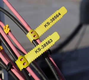 Gele WrapTags met serienummers op roze en zwarte kabels in buiteninstallatie