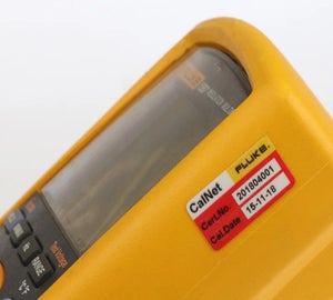 Kalibratielabel in rood-wit met certificaatnummer en datum op een meetapparaat