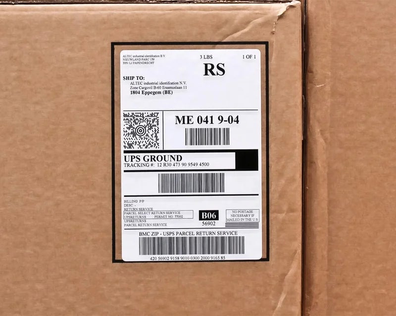 Papieren verzendlabel met adresgegevens en barcodes aangebracht op een kartonnen verzenddoos
