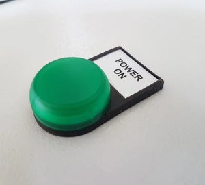 Wit ResoPrint label in drukknophouder bij groene drukknop met tekst power on