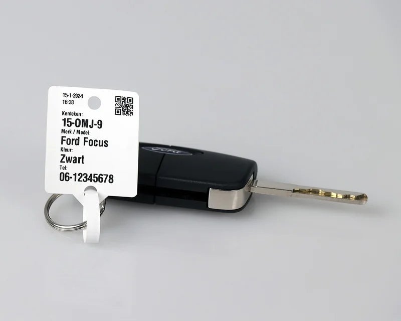 Wit sleutellabel met kenteken en voertuiginformatie bevestigd aan autosleutel met sleutelring