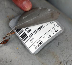 Persoon verwijdert het transparante beschermlaminaat van een KettleTag met barcode en identificatiegegevens