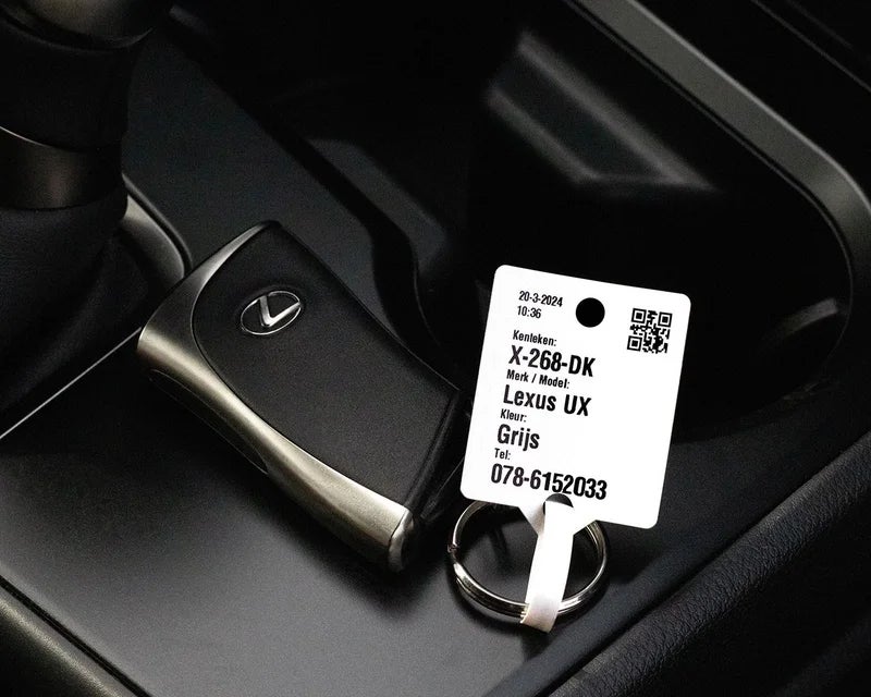 Sleutellabel met QR-code en voertuiggegevens aan autosleutel in auto interieur