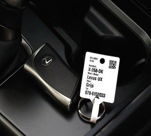 Sleutellabel met QR-code en voertuiggegevens aan autosleutel in auto interieur