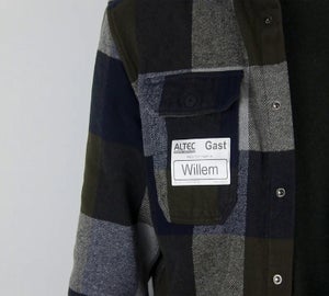 Verwijderbaar kledinglabel met naam en bezoekersaanduiding aangebracht op een geruite jas