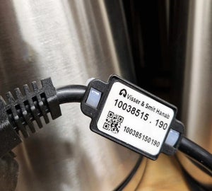 RFID Print & Laminate label bevestigd met zwarte HoseTag XL om industriële kabel
