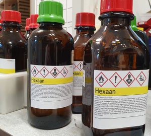 GHS labels met gevarensymbolen op bruine chemicaliënflessen